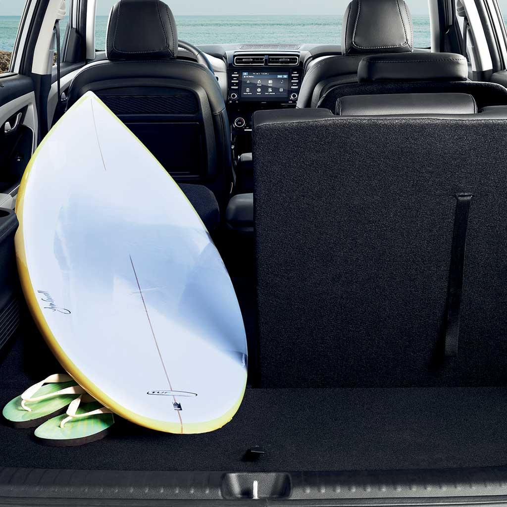 Tabla de surf y sandalias colocadas encima de un asiento abatible de Hyundai Creta Grand