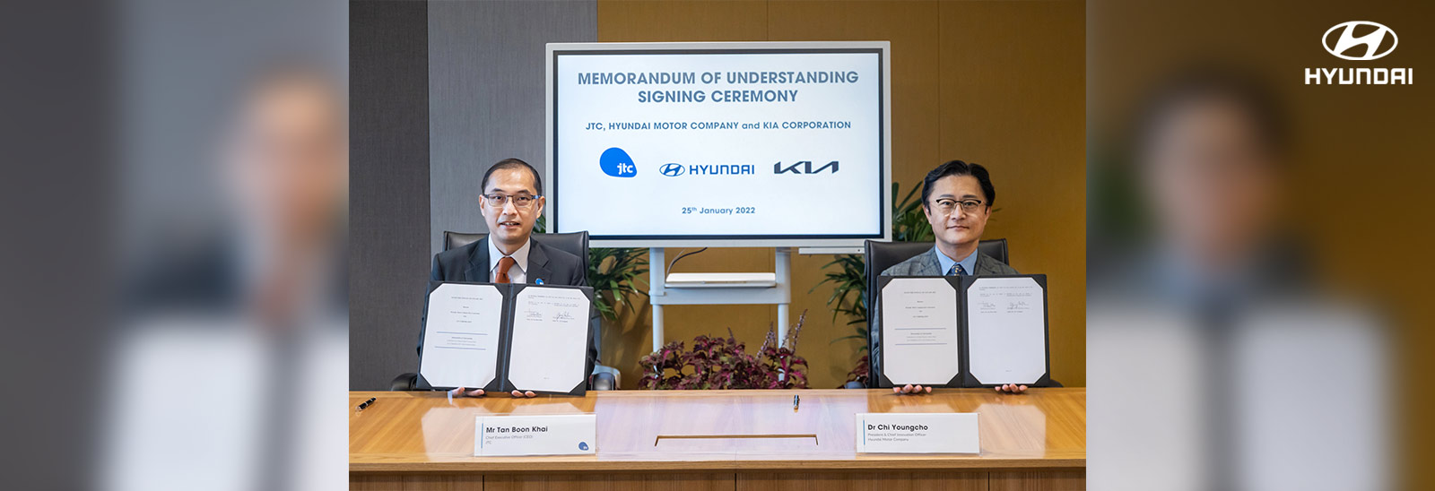 Ejecutivos de Hyundai y JTC mostrando carpeta con acuerdo