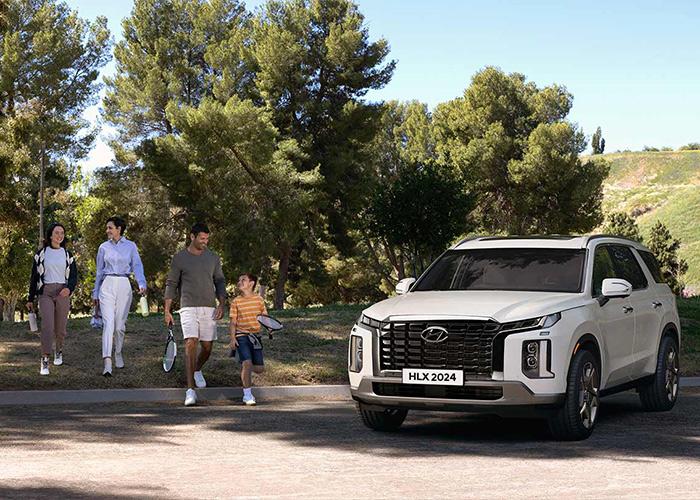 Familia caminando en grupo junto a una Hyundai Palisade color blanca