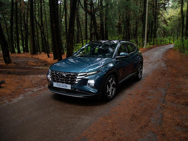 Vista tres cuartos de Hyundai Tucson color azul en el bosque