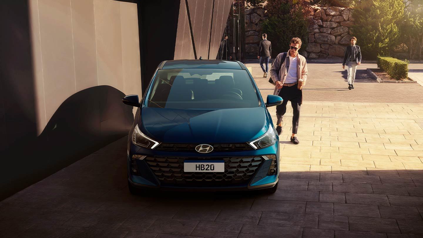 Joven caminando hacia un Hyundai HB20 Hatchback color azul