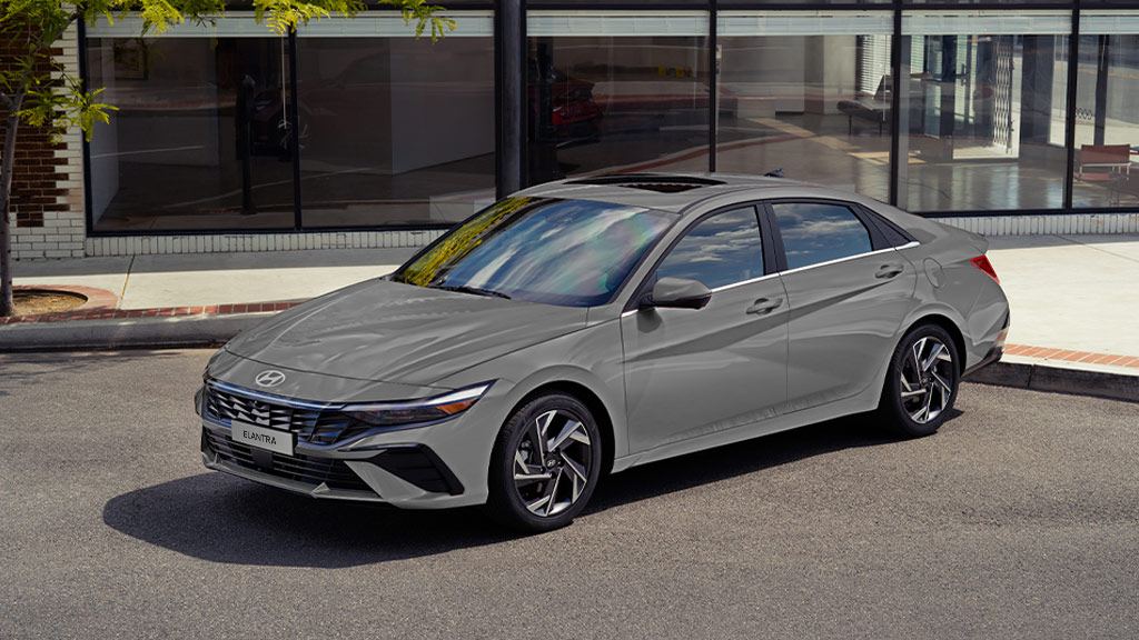 nuevo elantra 2026 vista 3/4 en gris, estacionado afuera de un edificio