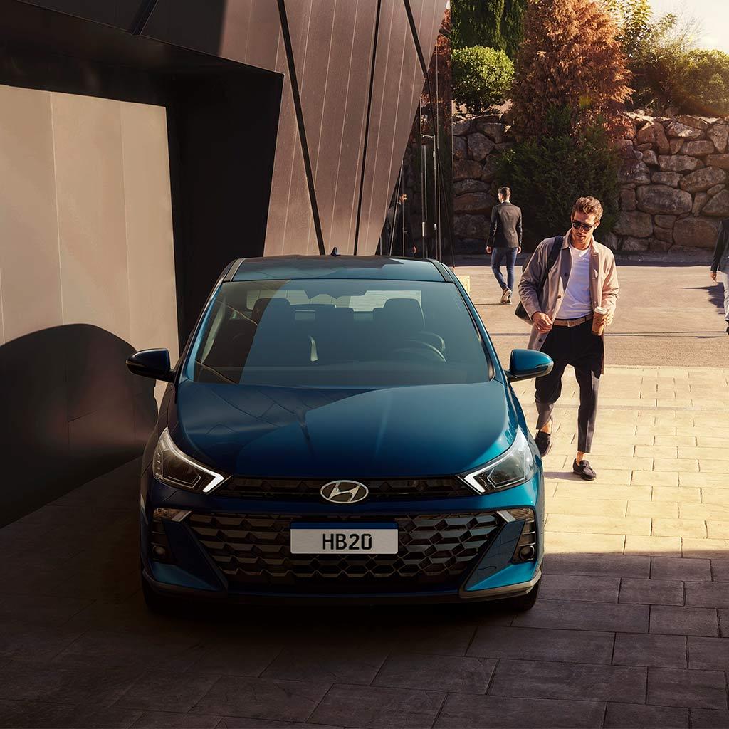 Joven caminando y observando un HB20 Hatchback color azul