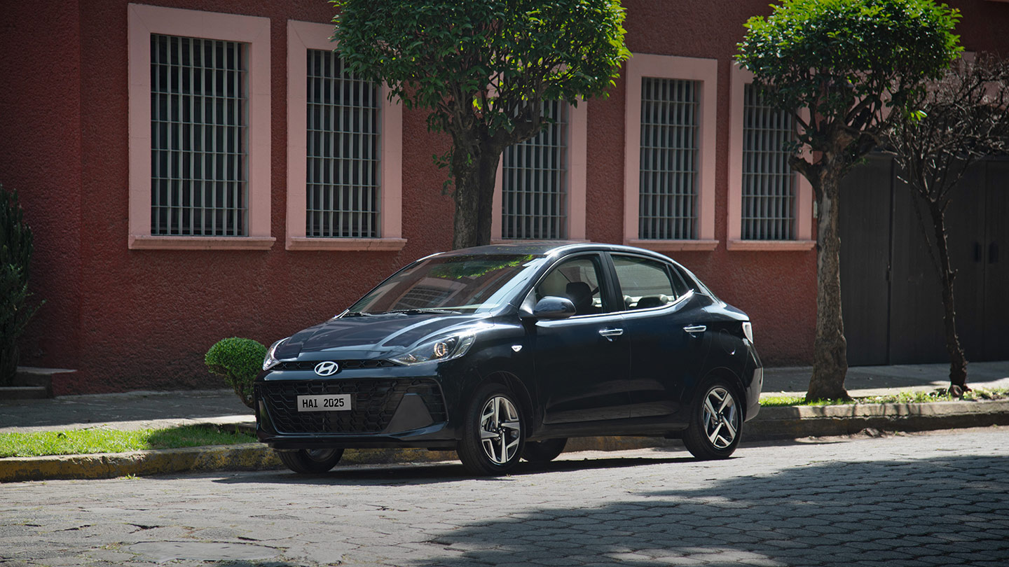 Hyundai Grand i10 Sedán color azul estacionado afuera de una casa estilo colonial