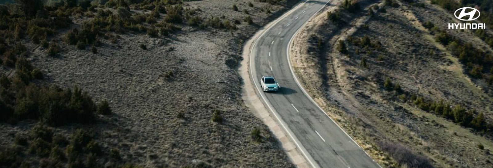 Auto Hyundai circulando por carretera en un terreno desértico