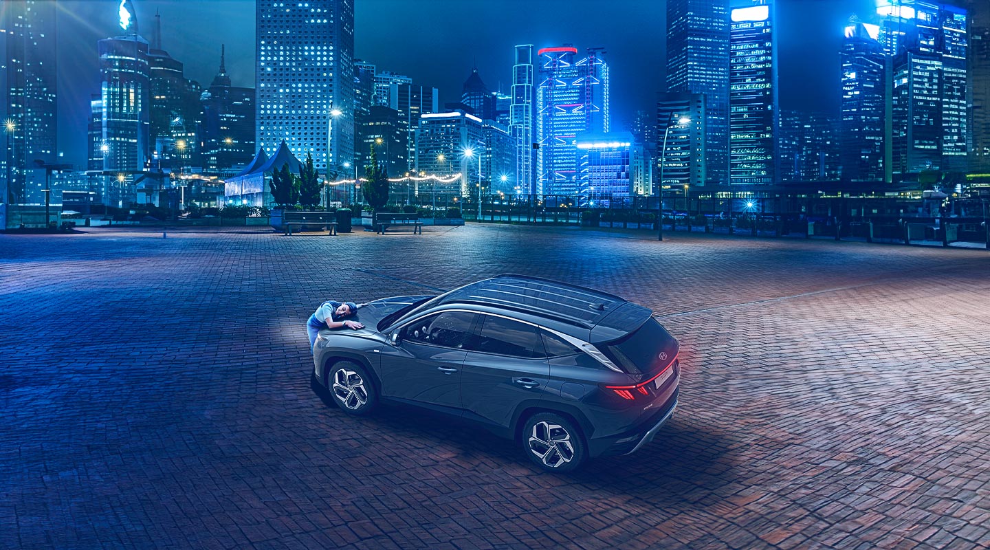 Mujer abrazanso su nueva Hyundai Tucson en medio de la ciudad